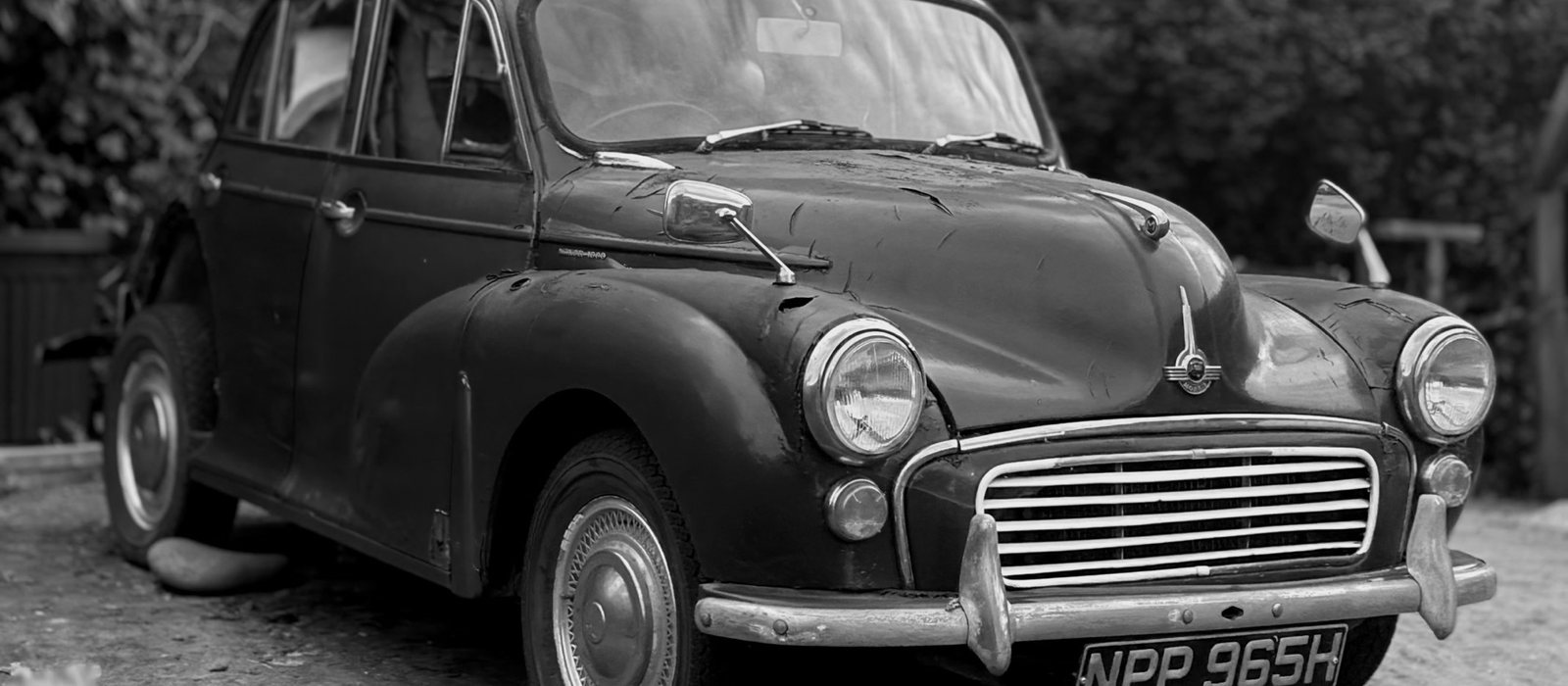 A Morris Minor 1000 four-door saloon in black and white, showing the bonnet, grille and chrome centre strip