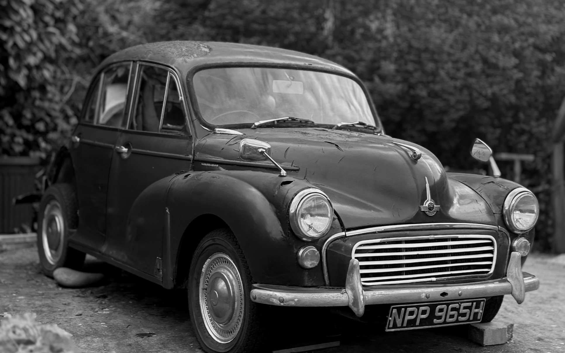 A Morris Minor 1000 four-door saloon photographed from the front three-quarter angle in black and white